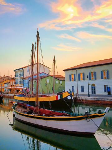 Colorful boats docked along a picturesque canal at sunset.