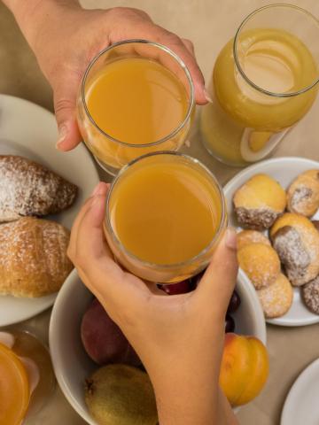 Frühstück mit Säften, Croissants und Keksen auf einem Tisch.